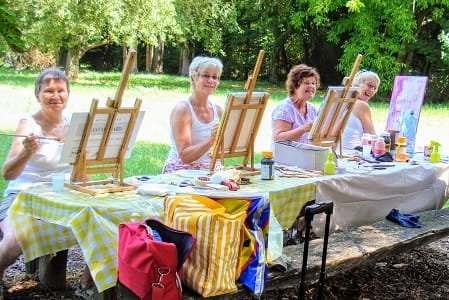 Vier dames heerlijk schilderen in het bos.